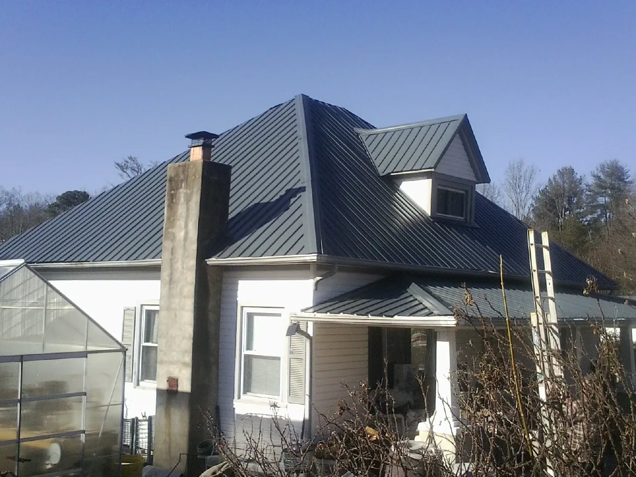 Dark blue standing seam metal roof on a white farmhouse with dormer — Slate & Tile Roof Repair by Roofing Brothers in Rogue River