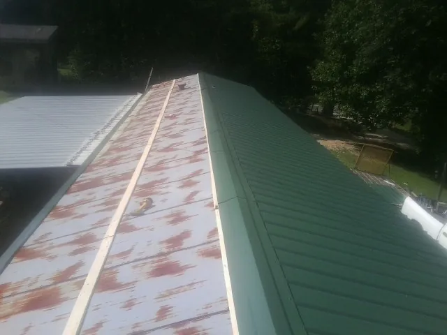 Old rusted panels beside newly installed green metal roofing — Wind Damage Roof Repair by Roofing Brothers in Rogue River