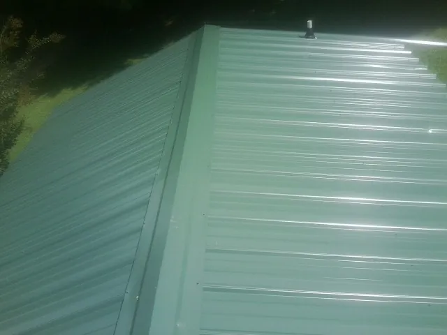 New green metal panels meeting at the ridge of a roof — Flat Roof Repair work by our crew in Rogue River
