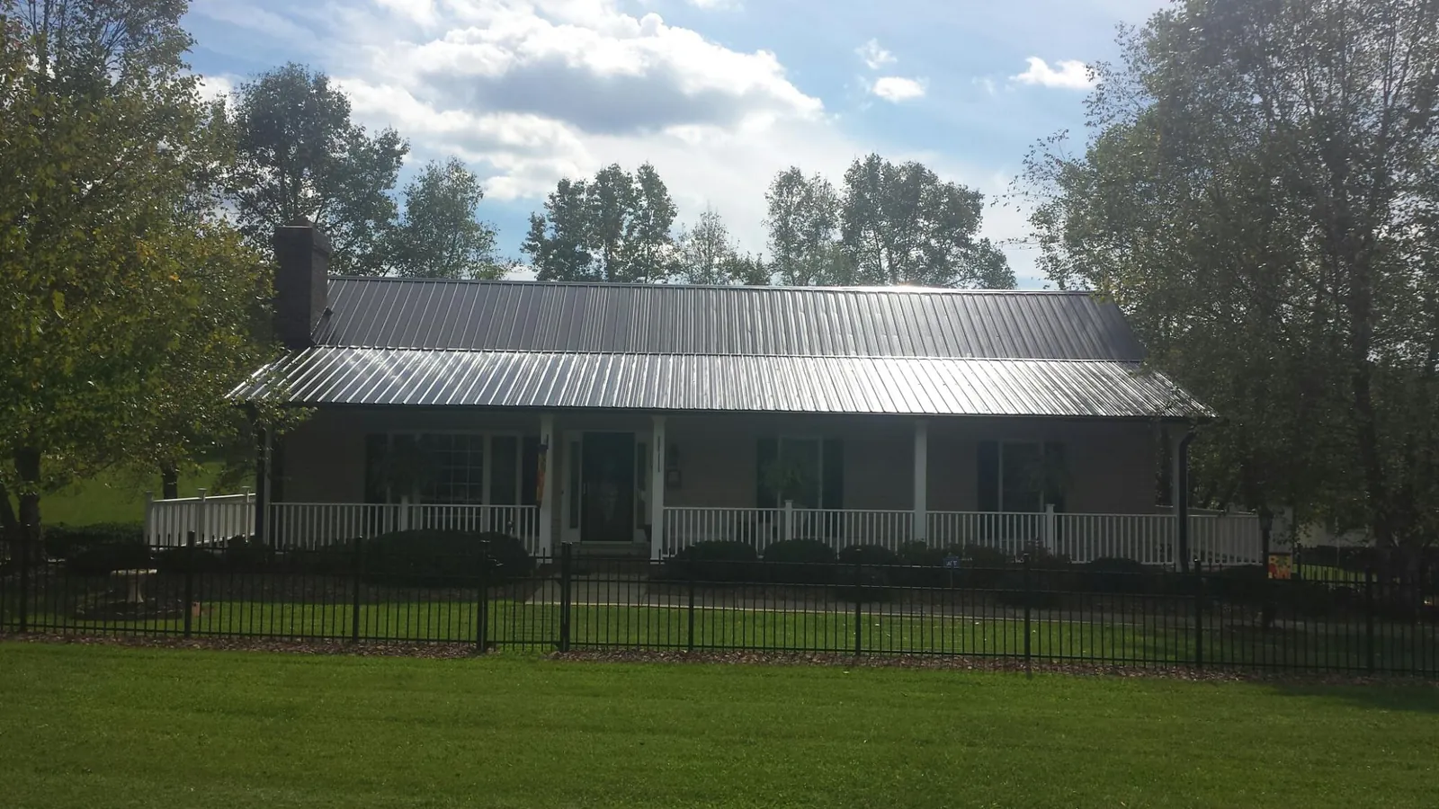 Gray metal roof on a brick ranch with a full width front porch — Gutter Guard Installation work by our crew in Rogue River