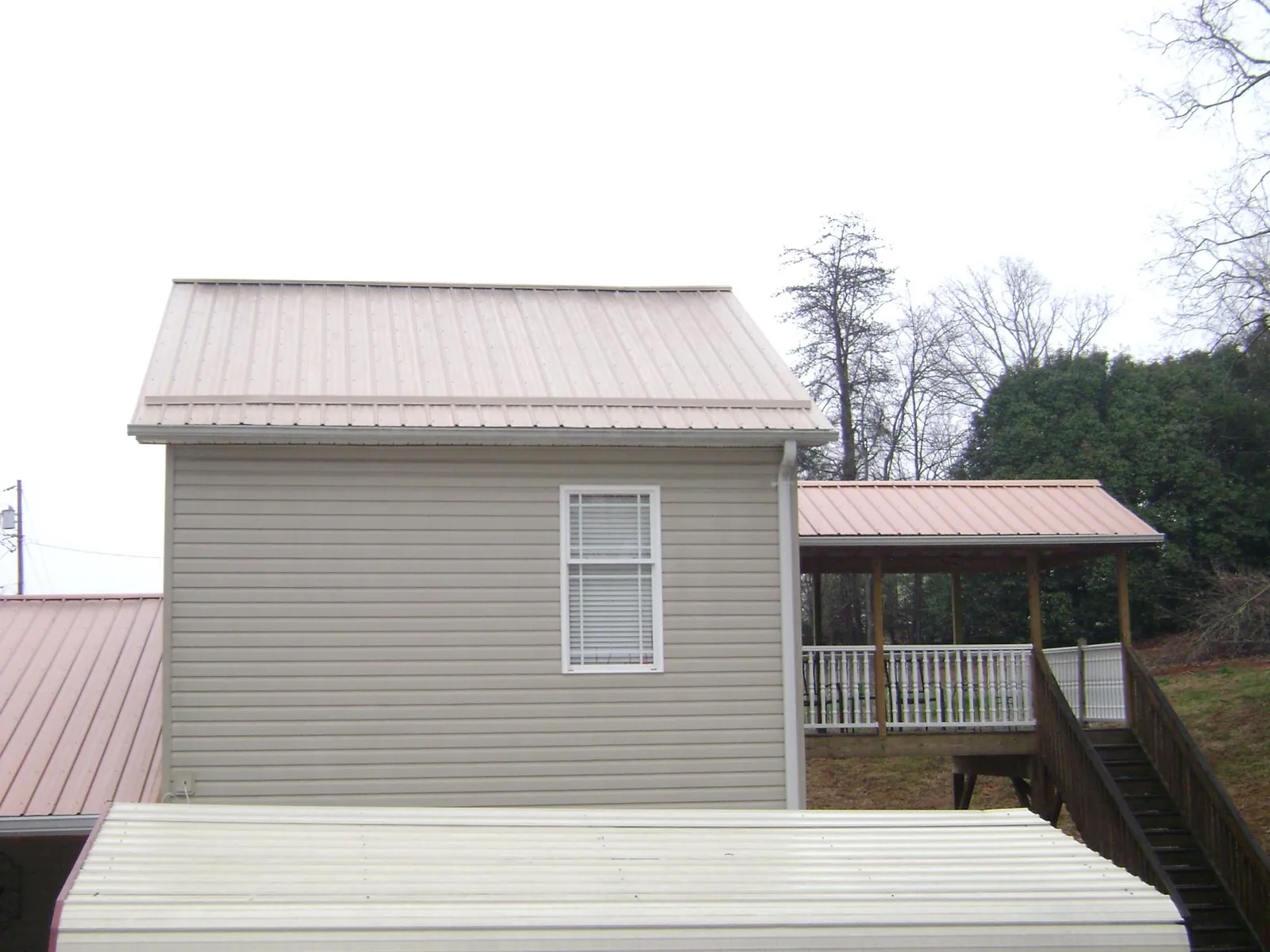 Tan metal roofs on a two story addition and attached porch, from a Roof Replacement job in Rogue River
