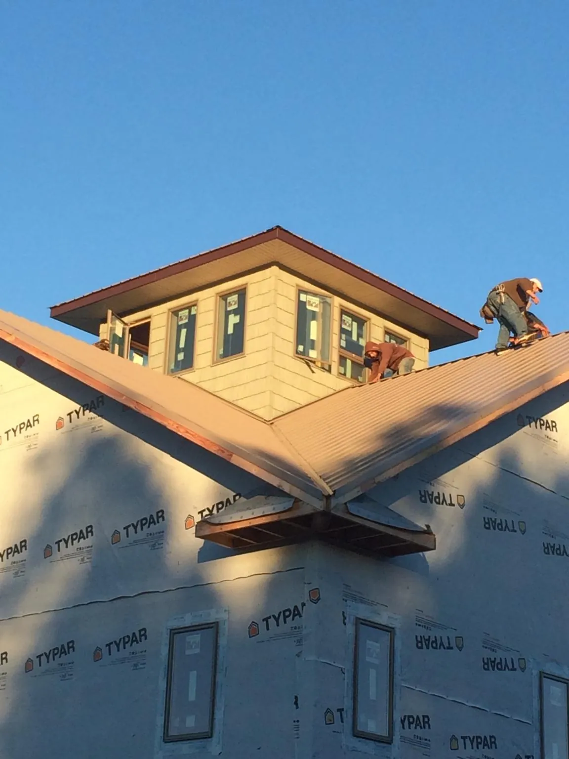 Roofers working around a rooftop cupola on a new metal roof at sunset — Roof Waterproofing in Rogue River by Roofing Brothers